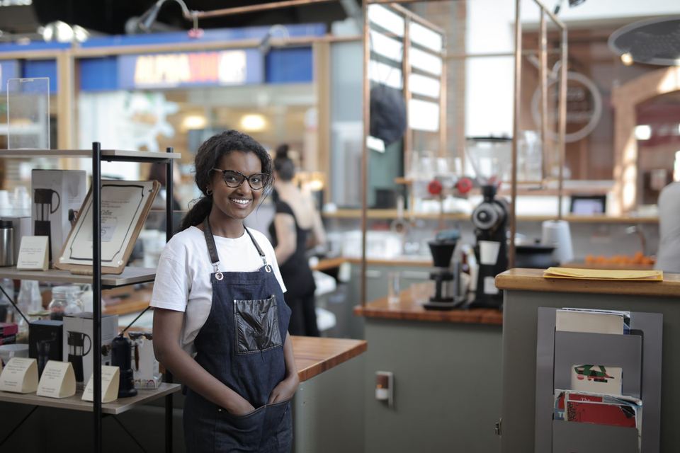 A café owner in an apron standing in her shop